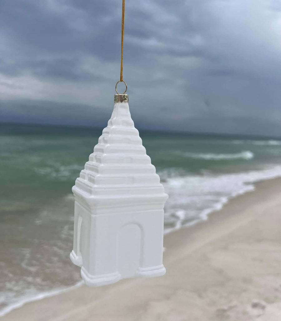White decorative buttery glass ornament on a beach with ocean in the background